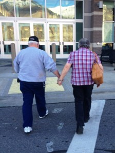 Old couple holding hands, walking