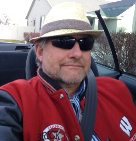 crushed crooked straw hat, sunglasses and a red Wisconsin jacket, looking sharp with a scruffy beard!