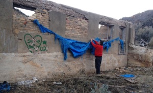 Final adjustments-- Blue drape'd graffiti wall, Thistle, Utah ghost town -- hanging